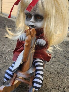 Spooky Blonde Doll in Red Dress with Striped Stockings and Wooden Rocking Horse